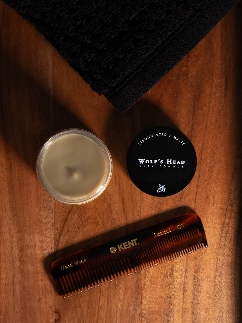 Open jar of Wolf’s Head Clay Pomade with lid beside it and a Kent Comb—matte finish, strong hold styling clay for natural texture and volume. Ideal for modern, everyday grooming.