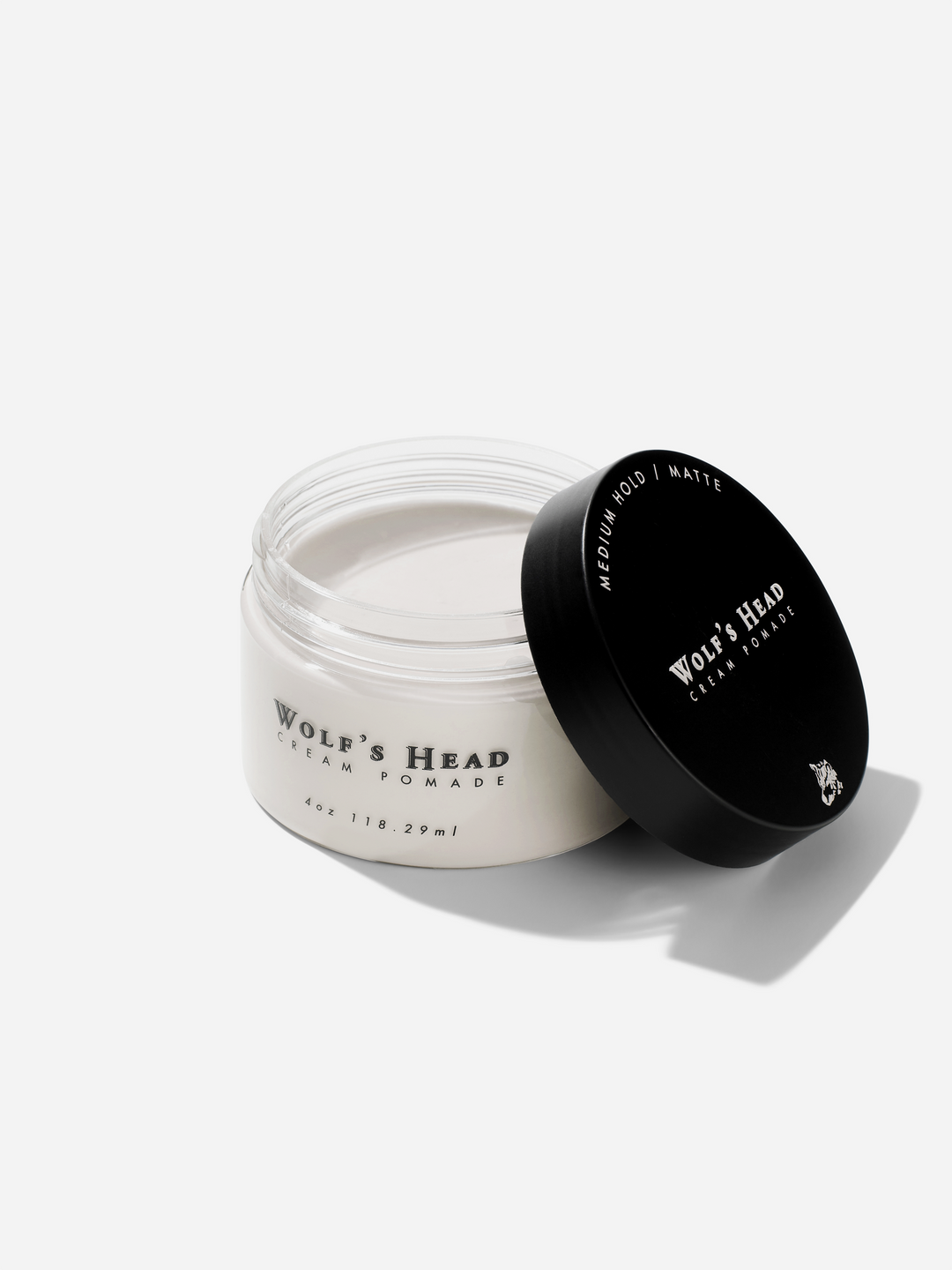 Open jar of Wolf’s Head Cream Pomade with lid beside it, medium hold pomade with a matte finish for soft, natural texture. Perfect for casual, everyday grooming.