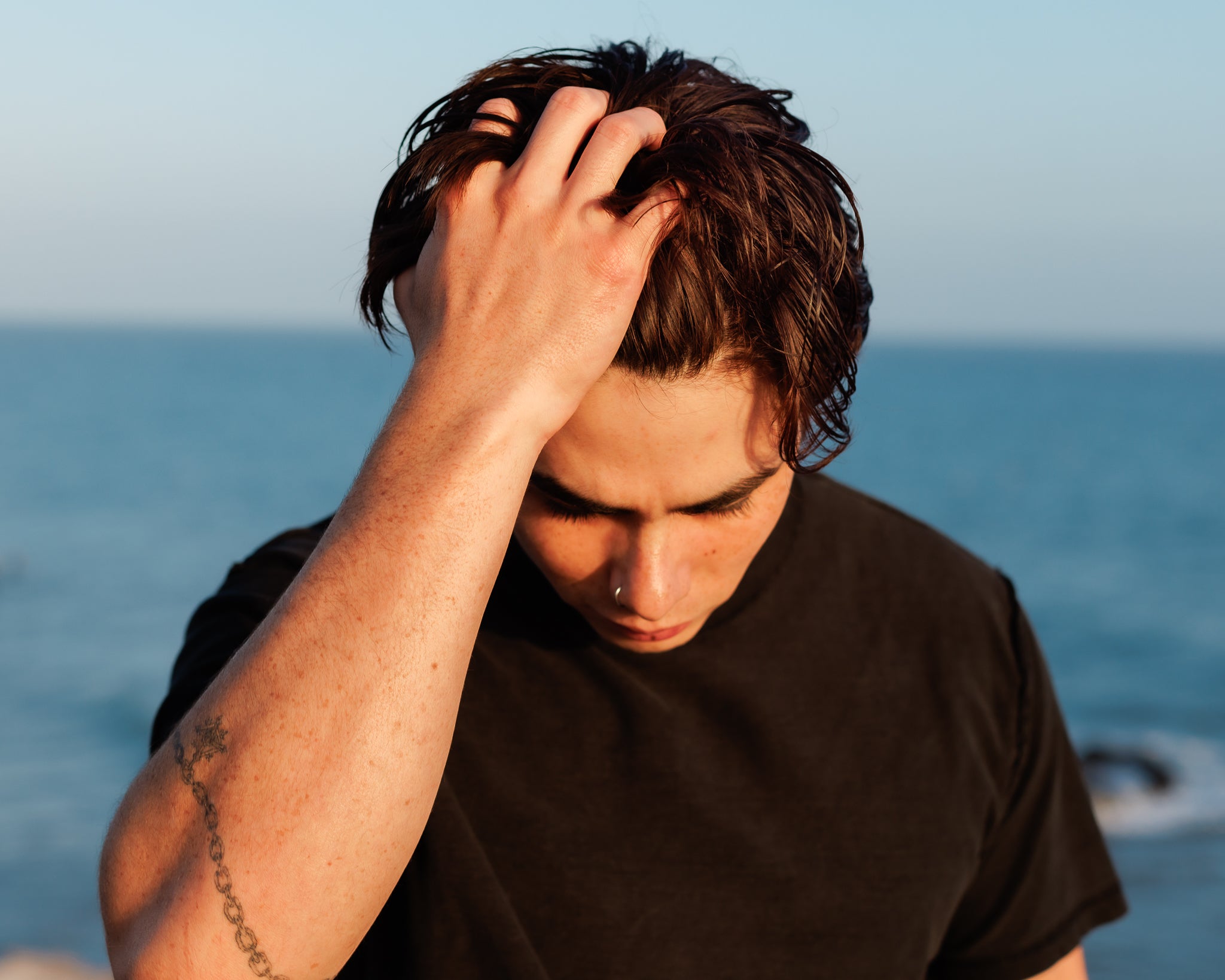 Man running his hand through mid-length hair—styled with Wolf’s Head grooming products for natural texture, healthy shine, and everyday control. Premium men’s hair care, made in California.