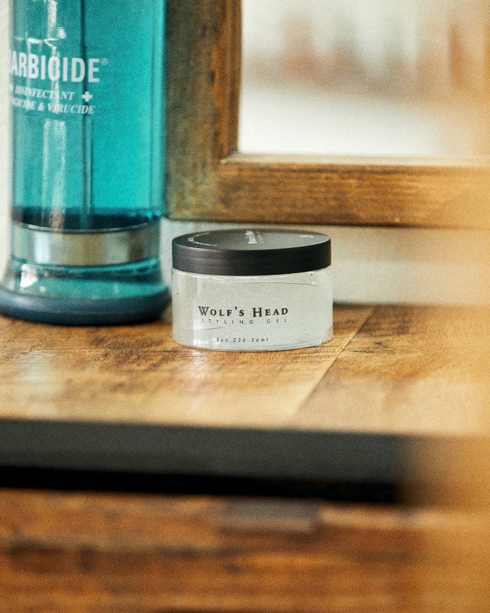 Wolf’s Head Styling Gel Pomade on barber station next to Barbicide – barbershop-tested - Strog Hold High Shine Finish hair product.  Ideal for slick backs, side parts, and polished hairstyles