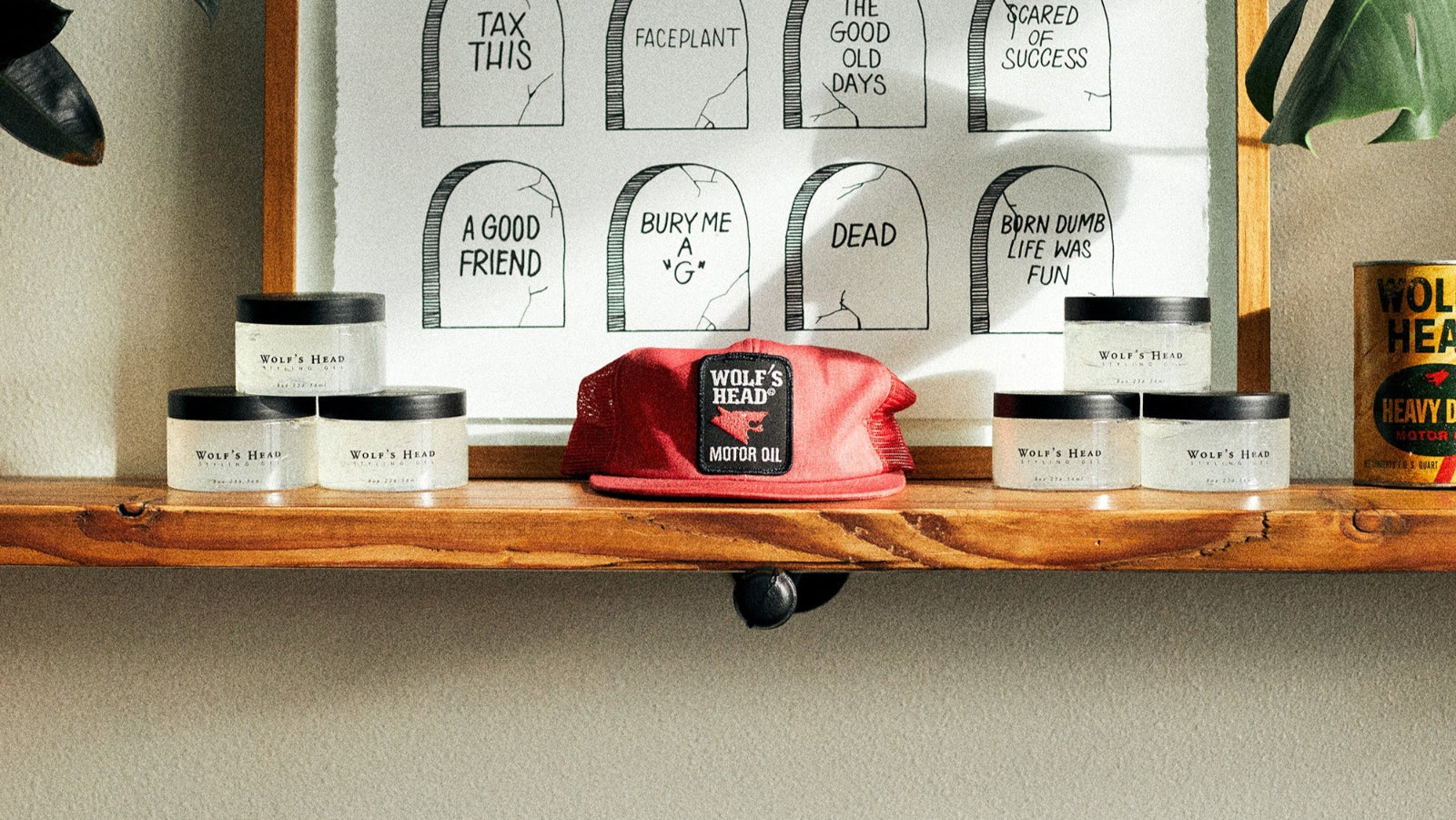 Wooden shelf merchandised with Wolf’s Head pomade jars, a red cap, and framed— Strong Hold High Shine water based pomades