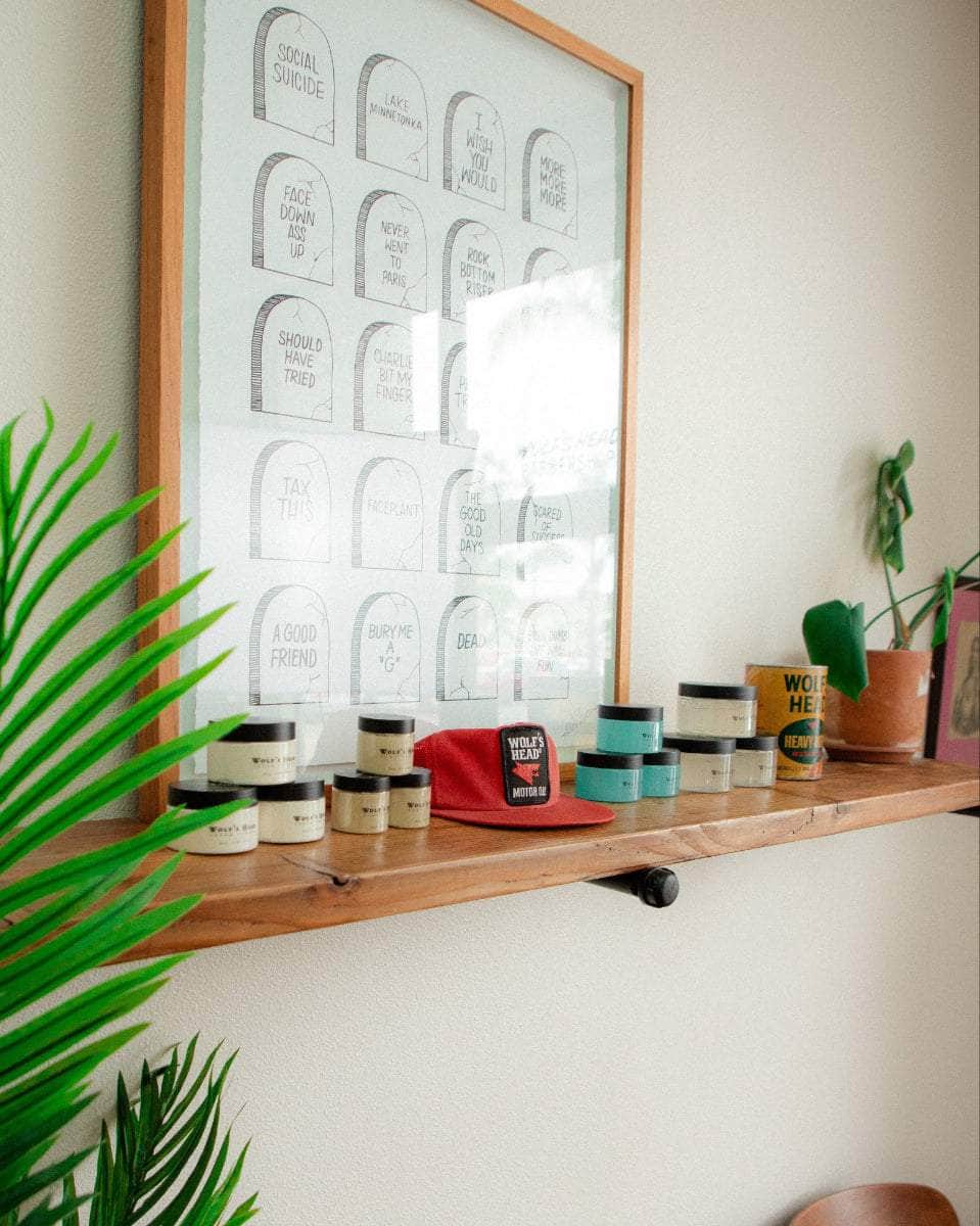 Wolf’s Head Pomade jars, framed art and vintage Motor Oil display on wood shelf – strong hold, matte and shine finish hair products made in California