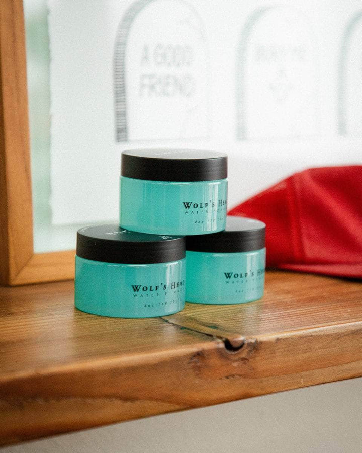 Wolf’s Head Water Soluble Pomades displayed on wooden shelf – strong hold shine finish - professional-grade grooming product trusted by California barbers